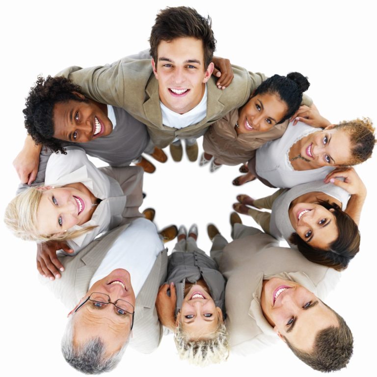 Gruppenshot von sieben Menschen, die lächeln und in einem Kreis stehen. Die Personen gucken nach oben und das Bild wurde von oben aufgenomme